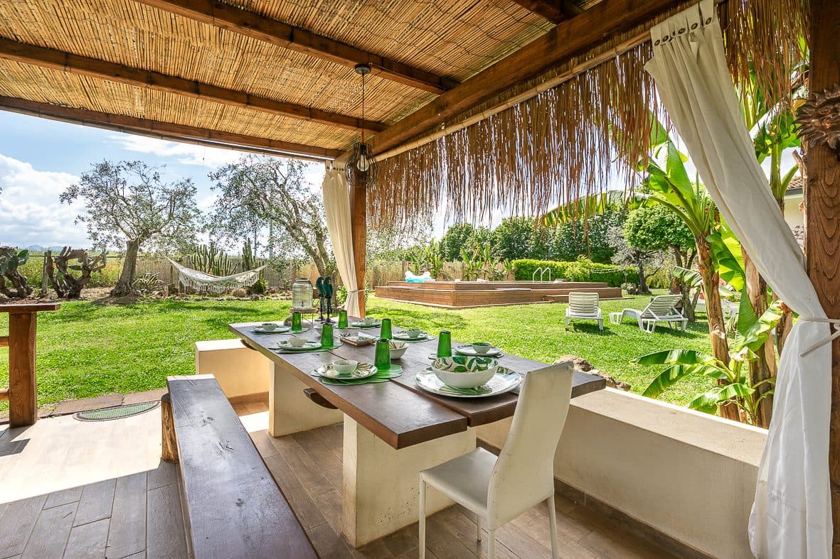 Wooden pergola with the outdoor table set for dinner